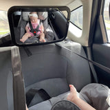 Reflection of a baby in a rear-facing car seat seen through the adjustable baby safety car mirror